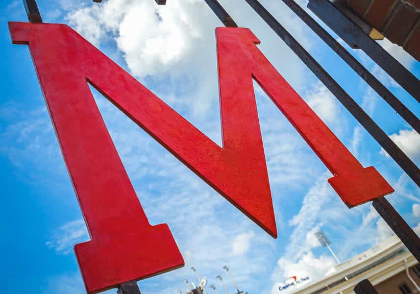 MEI2 Energy Seed Grants: Wrought iron red M Gate against brick outside of Maryland Stadium.